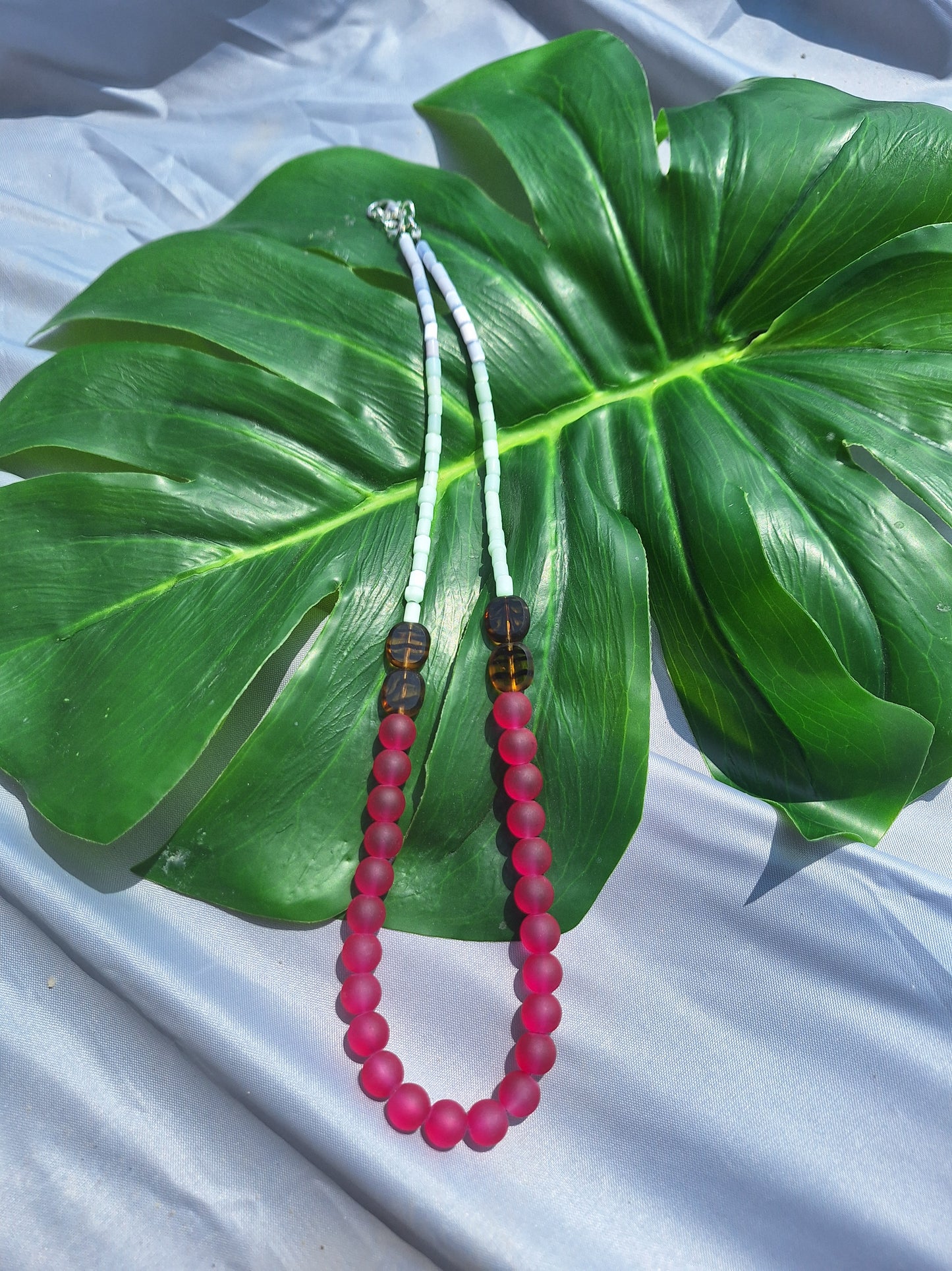 NEcklace on a large green leaf with a light gray background